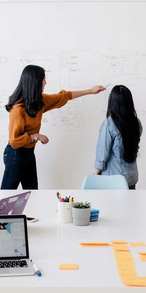two person working on a board in a meeting room